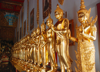 golden buddha statues stand in the public buddhist temple