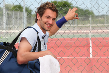 Tennis player leaning against fence