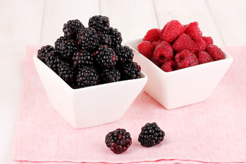 Ripe raspberries and brambles on wooden table