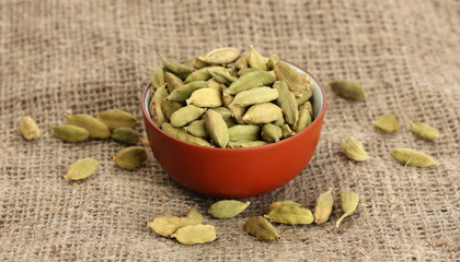Green cardamon in ceramical bowl on canvas background close-up