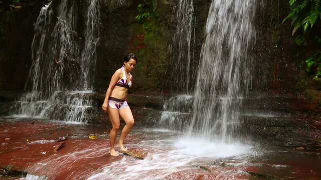 sexy woman passing through waterfall in borneo rainforest
