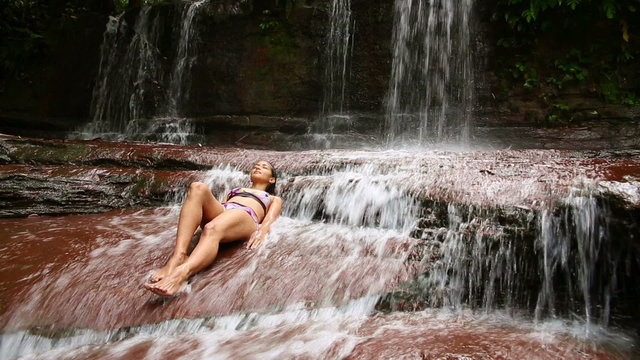 sexy girl with bikini lying down in waterfall river