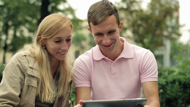 Young happy couple with tablet computer in the city