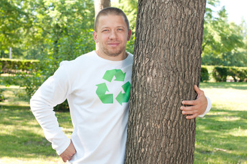 Being eco friendly: an adult man embracing a tree in summer park