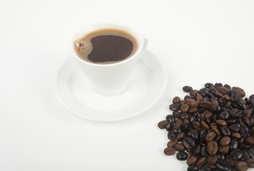 Cup of black coffee on a saucer on roasted coffee beans 