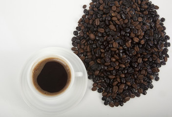 Cup of black coffee on a saucer on roasted coffee beans 