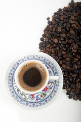 Cup of black coffee on a saucer on roasted coffee beans 