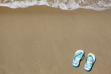 Blue beach slippers on sandy beach with copy space for text, sum