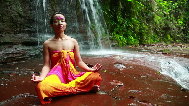 Meditating with Facial Painting in borneo rainforest waterfall