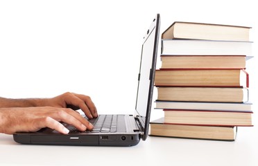 man working on computer with pile of books back