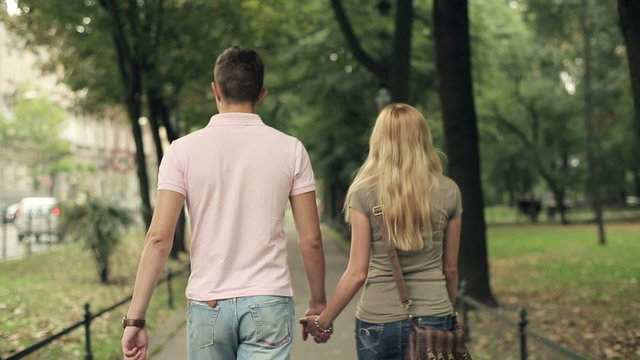 Happy young couple walking in the park, steadicam shot