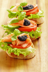 Three sandwiches with salmon and caviar