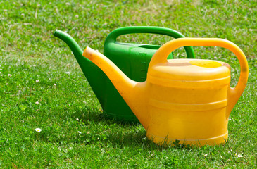 two watering cans on a green fie
