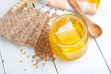 honey with a wooden spoon and crispbread on wooden background