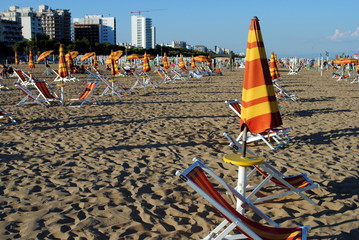 beach umbrellas and sunbed over sand at the sunset