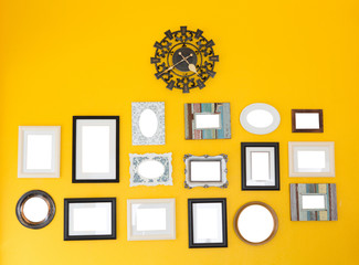Several frames with vintage clock on the yellow wall