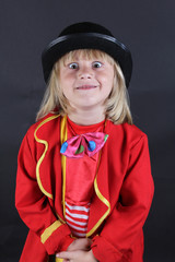Foto de niño rubio mirando a cámara disfrazado de payaso. vestido con sombrero negro y traje rojo. Concepto de comedia, cómico