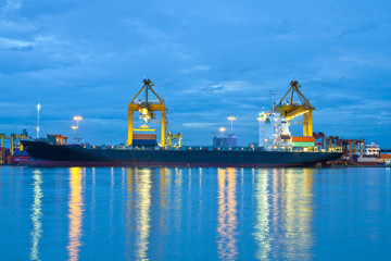 Container Cargo freight ship with working crane bridge in shipya