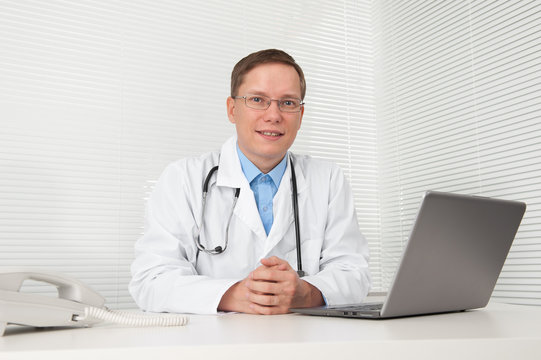 Doctor with laptop at desk in office