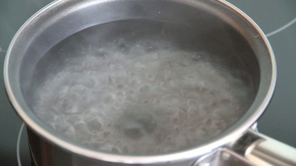 Steam of boiling water on stove in kitchen