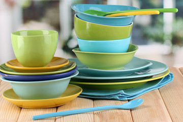 Colorful tableware on wooden table on window background