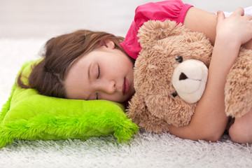 Young girl taking a nap with her teddy bear