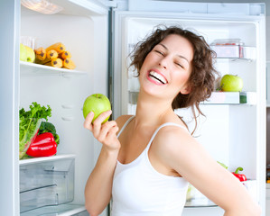 Beautiful Young Woman near the Refrigerator with fresh apple