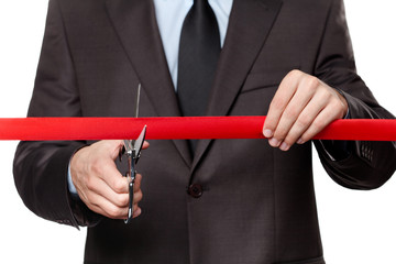 A man cutting a scarlet satin ribbon with scissors