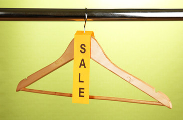 wooden clothes hanger as sale symbol on green background.