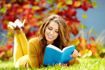 Portrait of a gorgeous brunette woman reading a book in the autu