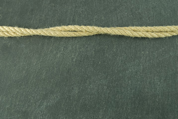 Wellenförmiges Seil auf Schieferuntergrund