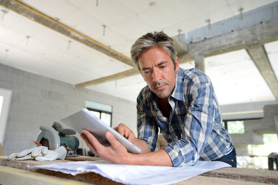 Entrepreneur in house under construction checking plan