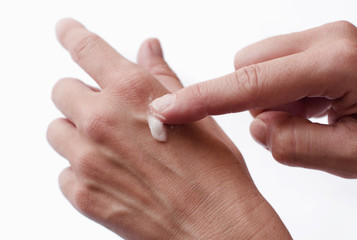 Female hands applying lotion over hand skin