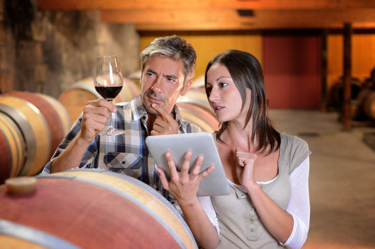 Winemakers in cellar using electronic tablet