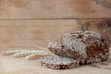 Vollkornbrot mit Weizenähren auf Holzbrett