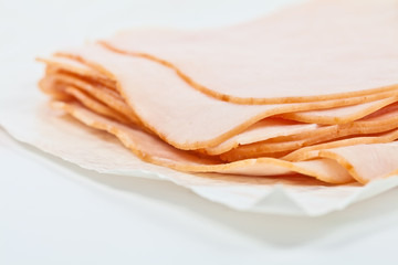 Turkey salami slices on the white paper, as wrapped in the store