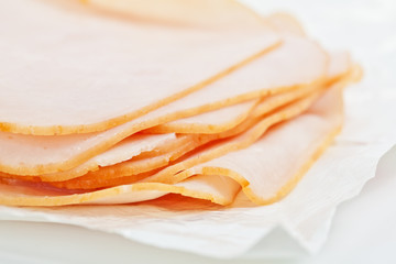 Turkey salami slices on the white paper, as wrapped in the store