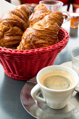Breakfast with coffee and croissants in a basket on table
