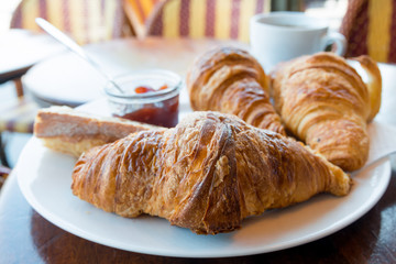 Breakfast with coffee and croissants in a basket on table