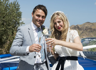 Bride and Groom next to the wedding car drinking champagne
