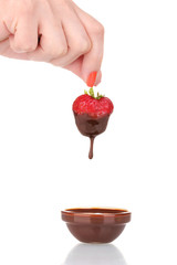 Hand holding strawberry in chocolate isolated on white