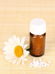 medicine bottle with tablets and flower on bamboo mat