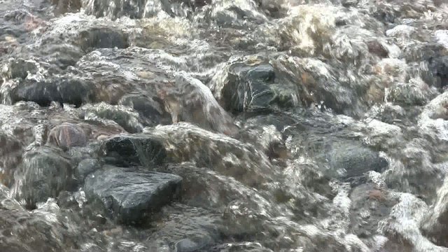 Close up of a stream flowing over stones on a beach