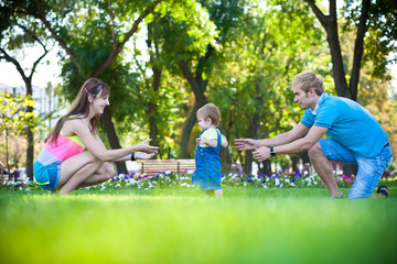 Fototapeta premium happy parents with a baby in a greenl summer park