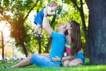 Fototapeta premium happy parents with a baby in a greenl summer park