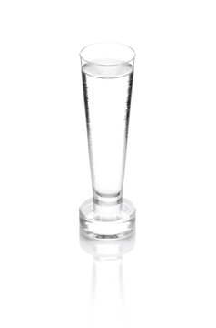 shot glass filled with clear cold alcohol isolated on white