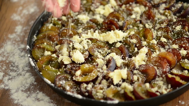 Pflaumenkuchen wird mit zweiter Portion Streusel bestreut