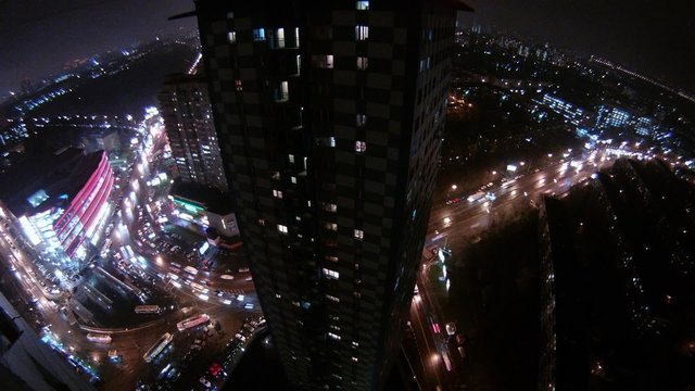 Skyscraper stand surrounded with freeways at night from above