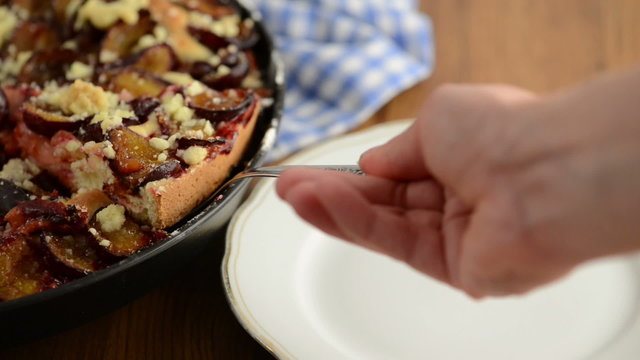 St&uuml;ck Pflaumenkuchen wird auf einen Teller gelegt