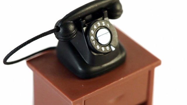 Black toy phone on small table circling isolated